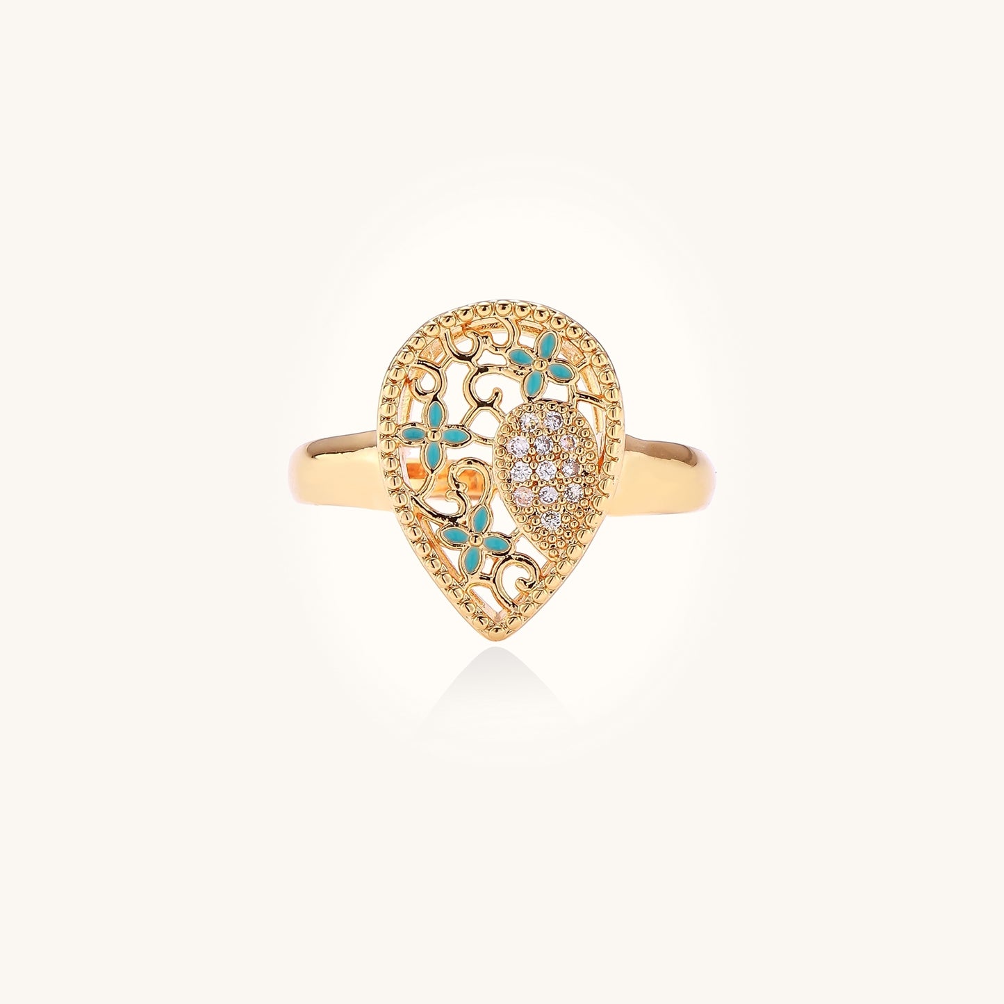 Gold-plated heart ring with turquoise enamel scrollwork and cubic zirconia stones on white background
