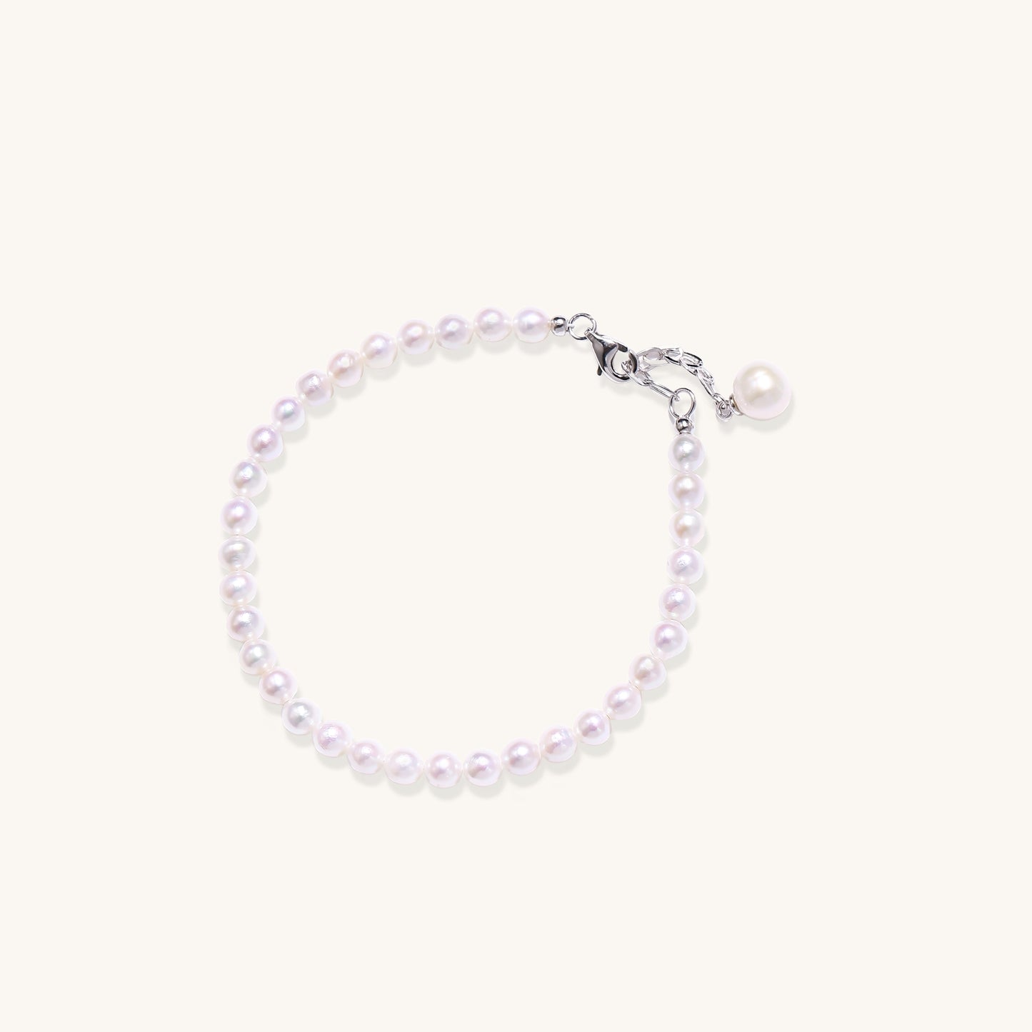 Delicate sterling silver bracelet with small freshwater pearls and adjustable chain on neutral background.