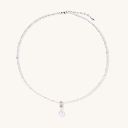 Delicate beaded necklace with lavender crystals, white pearls, and crystal pendant with pearl drop on white background.