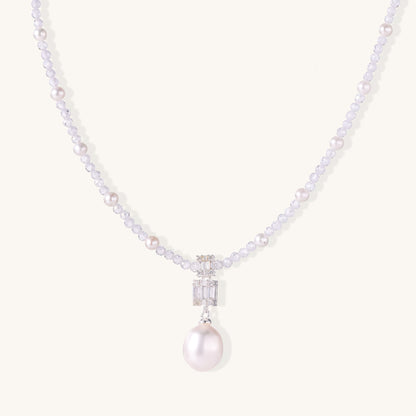 Delicate beaded necklace with lavender crystals, white pearls, and crystal pendant with pearl drop on white background.