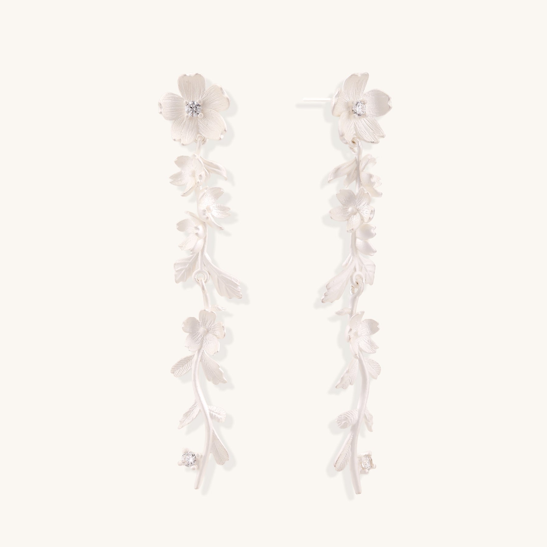 Pair of sterling silver dangle earrings with intricate leaf vine patterns and crystal accents on white background.
