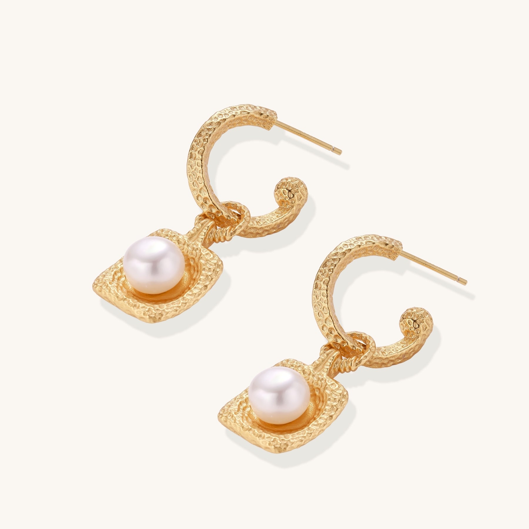 Gold-plated textured hoop earrings with square pendants containing freshwater pearls on white background
