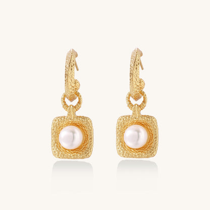 Gold-plated textured hoop earrings with square pendants containing freshwater pearls on white background