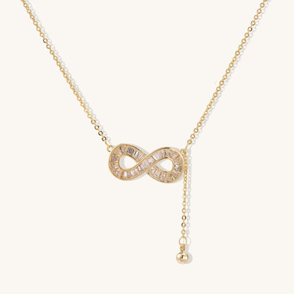 Delicate 14K gold plated infinity pendant with crystal accents on adjustable chain with small ball charm detail.