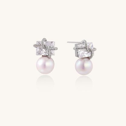 Gold-plated stud earrings with square crystal tops wrapped in twisted wire and freshwater pearl drops on white background