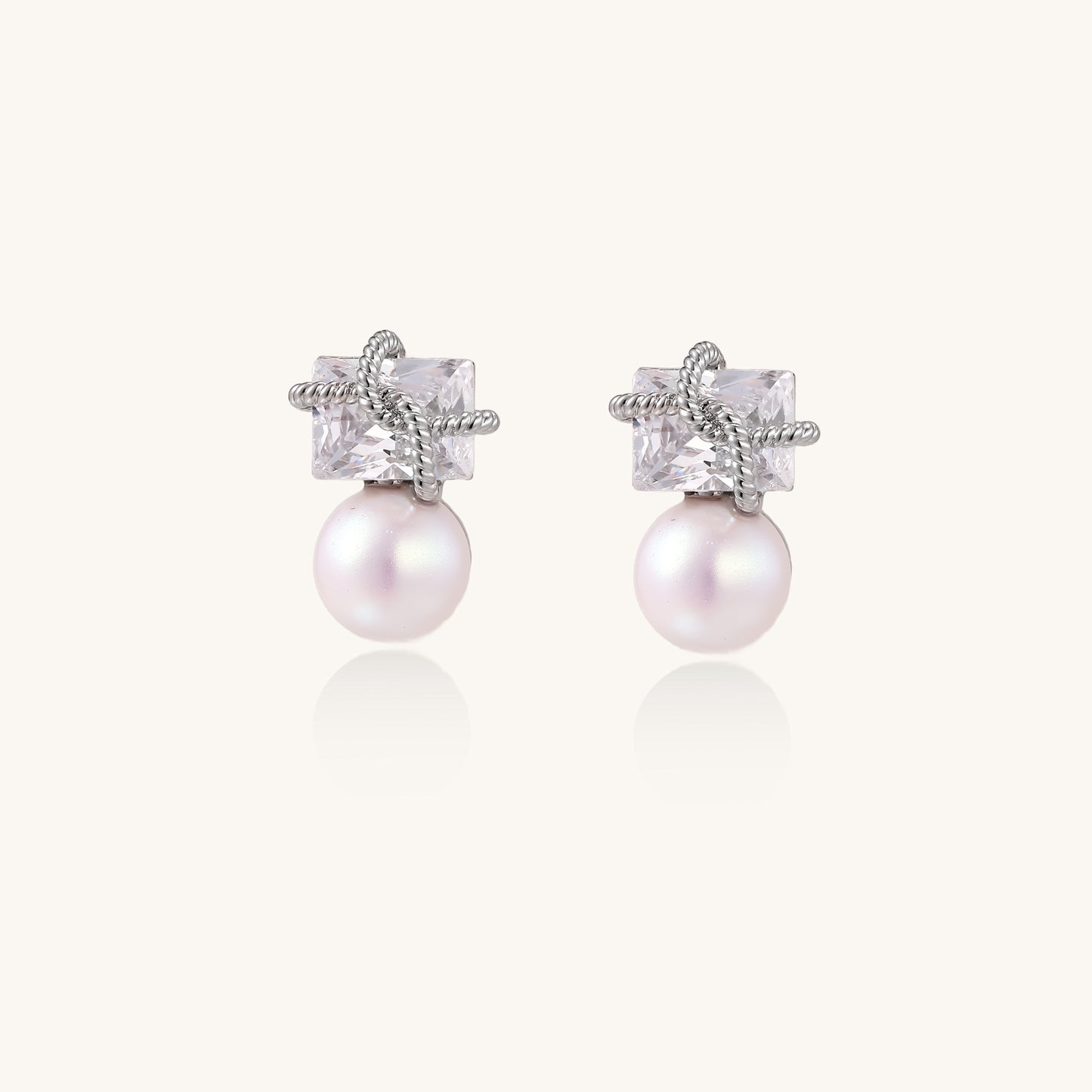Gold-plated stud earrings with square crystal tops wrapped in twisted wire and freshwater pearl drops on white background