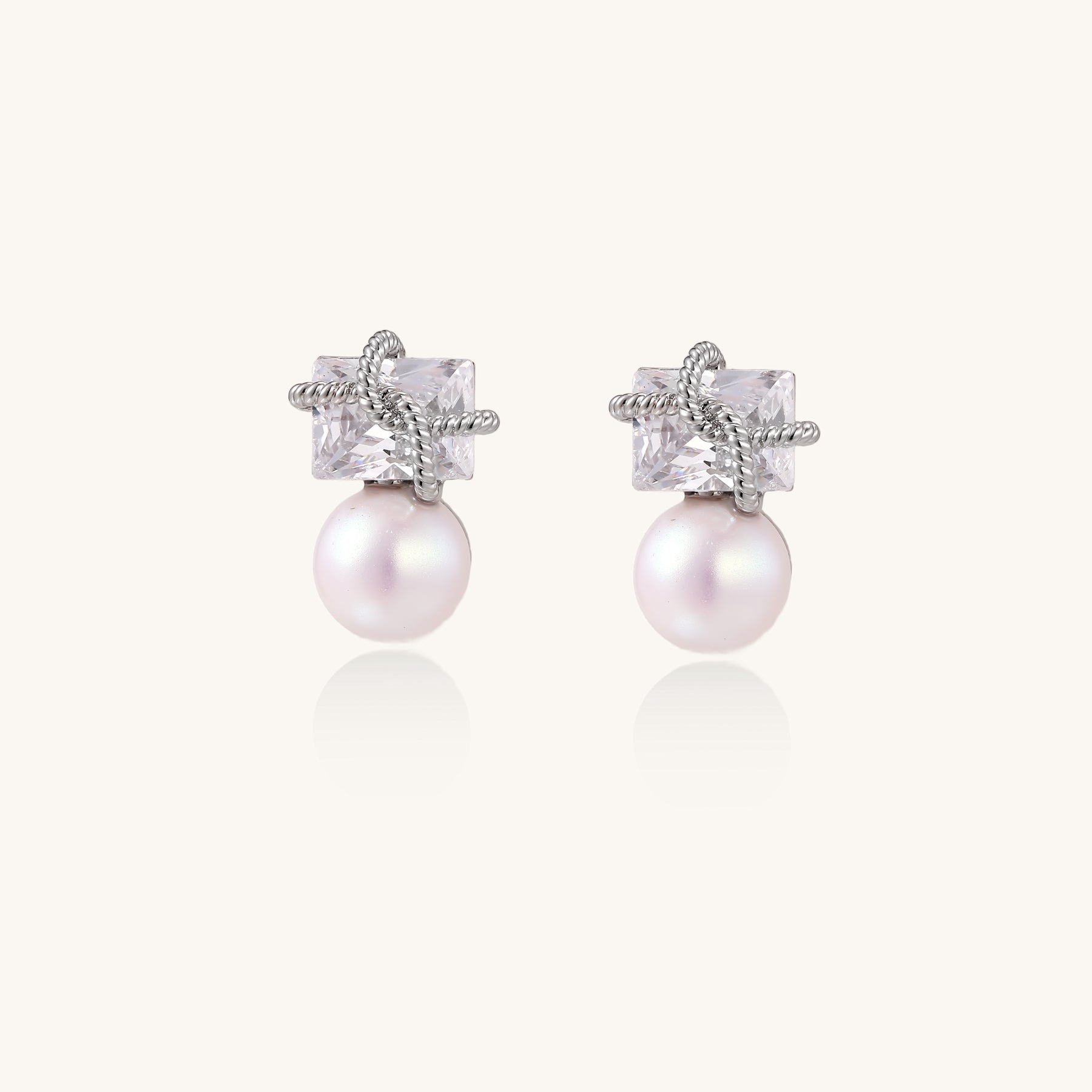 Gold-plated stud earrings with square crystal tops wrapped in twisted wire and freshwater pearl drops on white background