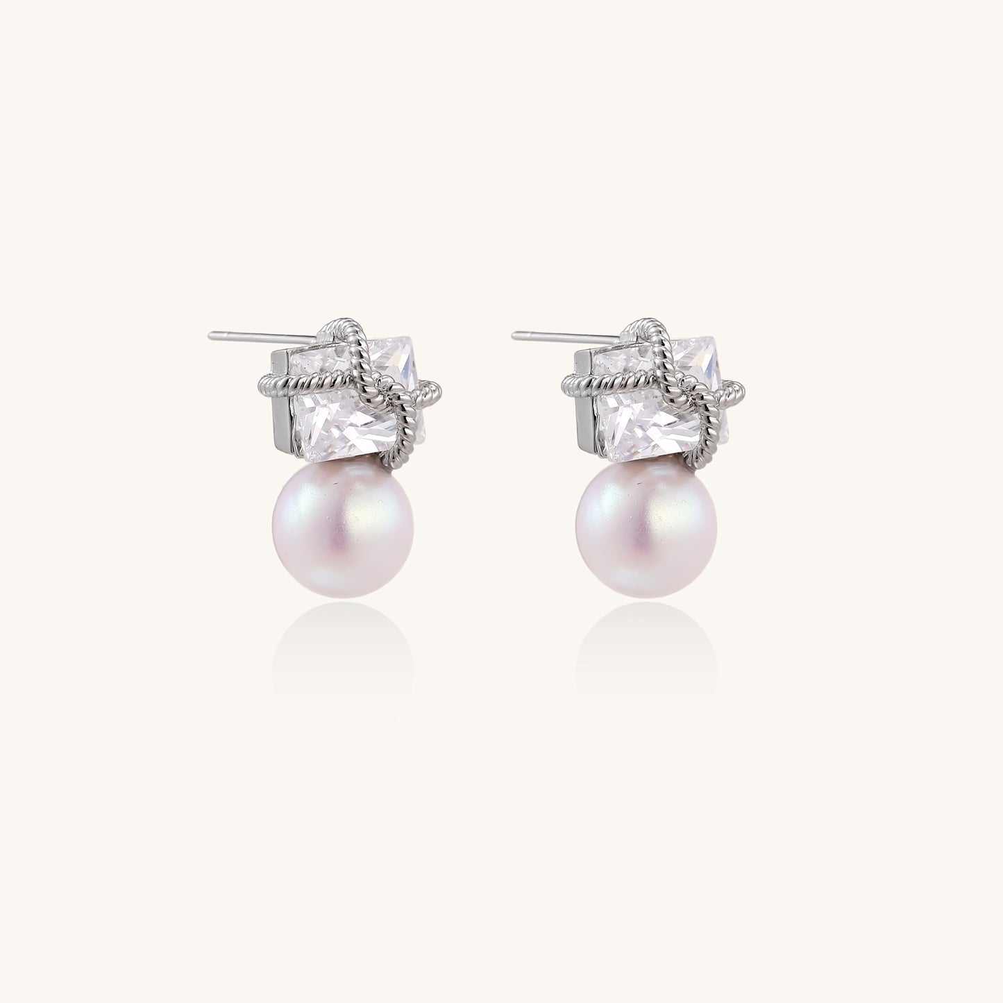 Gold-plated stud earrings with square crystal tops wrapped in twisted wire and freshwater pearl drops on white background