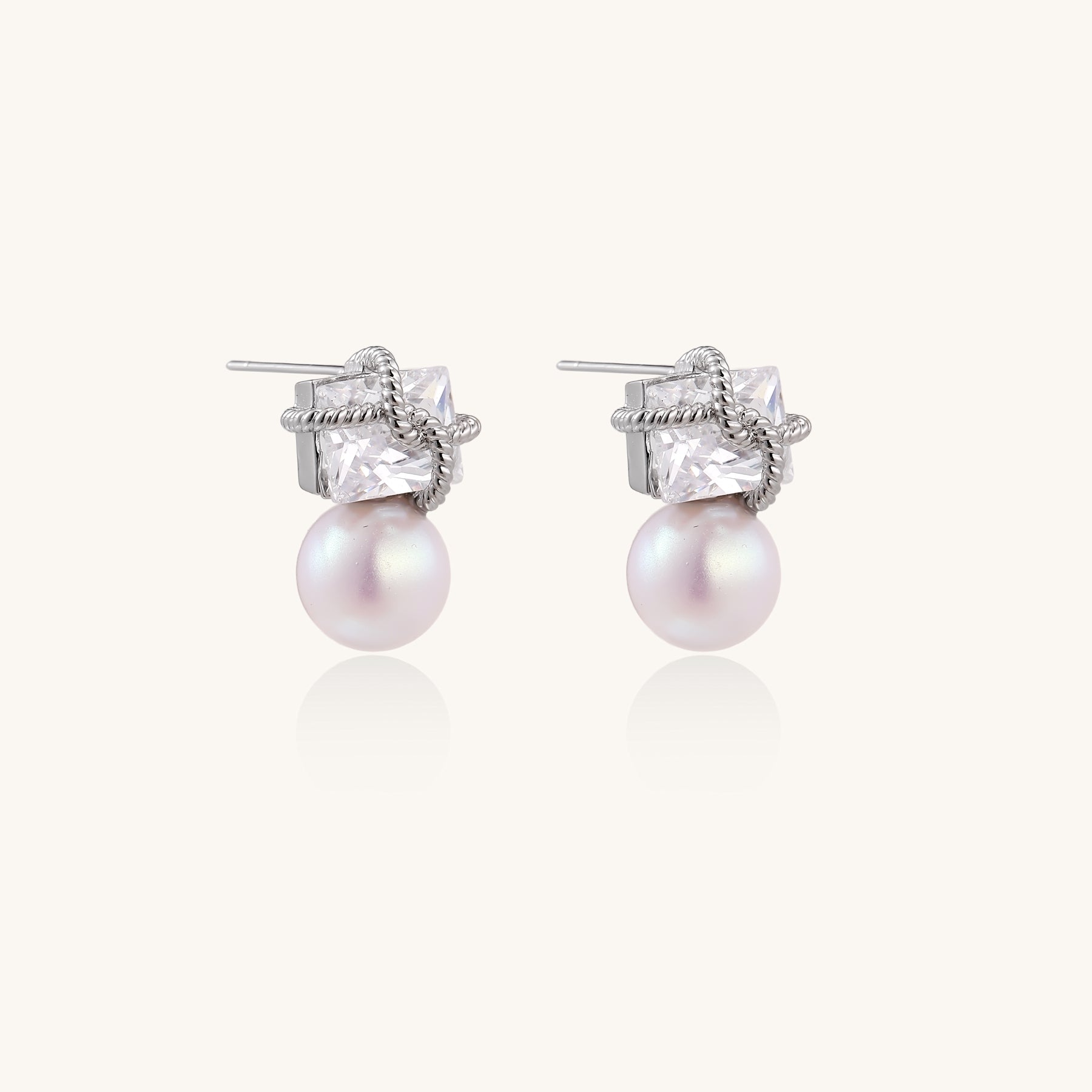 Gold-plated stud earrings with square crystal tops wrapped in twisted wire and freshwater pearl drops on white background