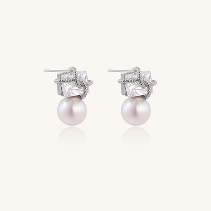 Gold-plated stud earrings with square crystal tops wrapped in twisted wire and freshwater pearl drops on white background