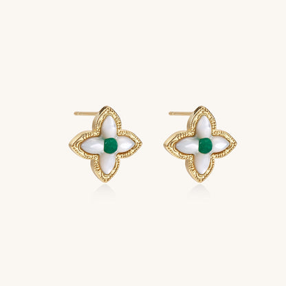 Dainty gold-plated quatrefoil stud earrings with white mother-of-pearl petals and green gemstone centers on beige background.