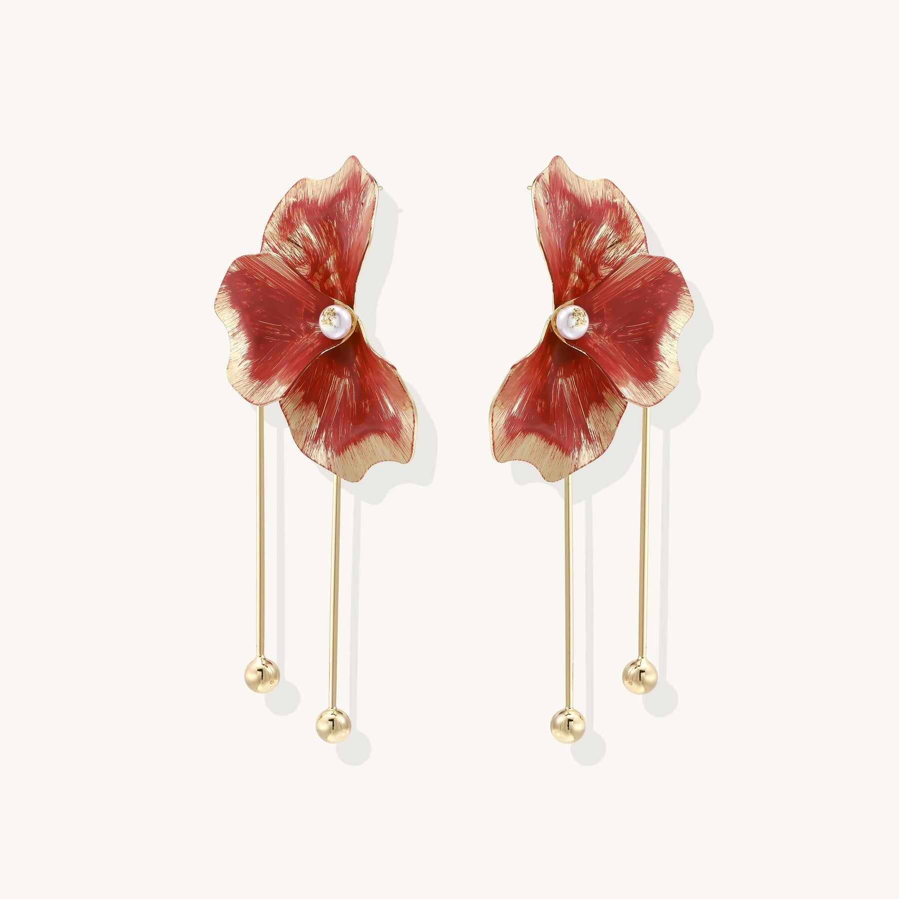 Statement drop earrings with coral-red enamel flower petals, gold-plated brass, and mother-of-pearl centers on white background