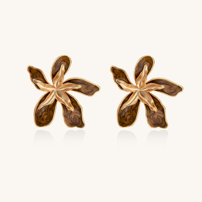 Large gold-plated flower earrings with brown enamel marbled petals on beige background, showing intricate floral design.