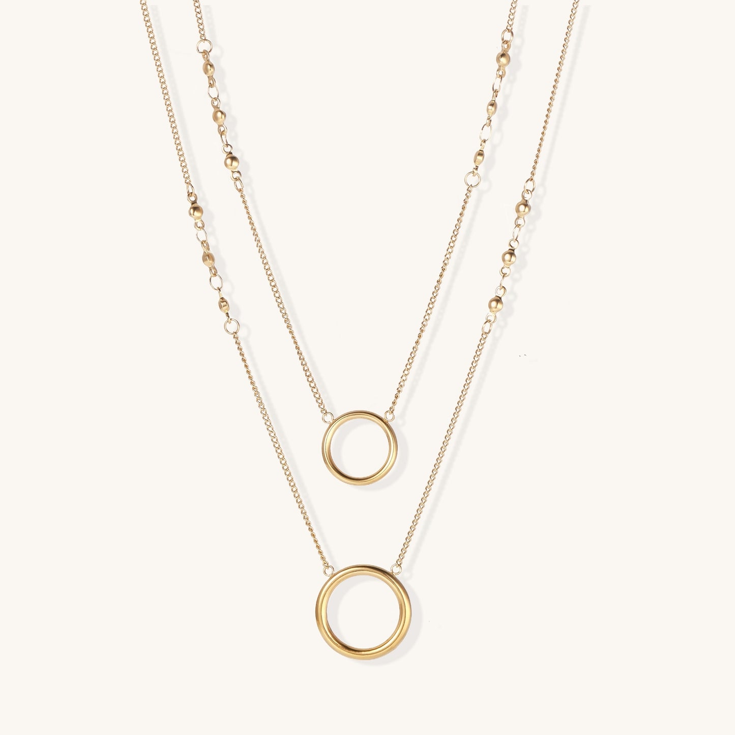 Gold-plated layered necklace set with two circular pendants featuring white centers on delicate chains.