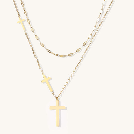 Two layered 14K gold-plated cross necklaces with adjustable chains on light background.