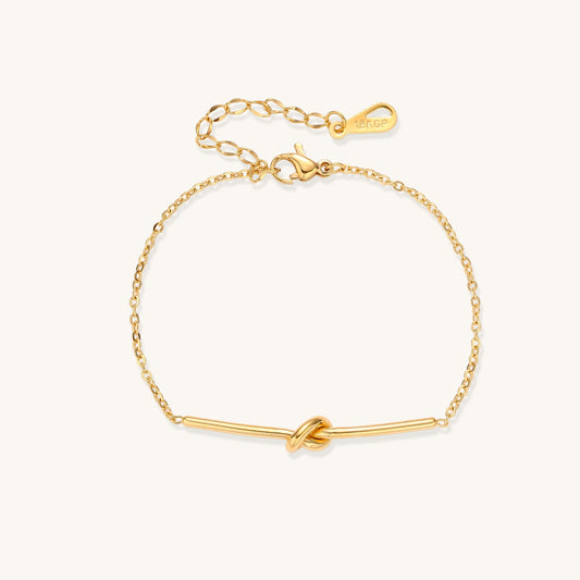 Delicate gold-plated chain bracelet with twisted knot bar detail and adjustable extender chain on white background.