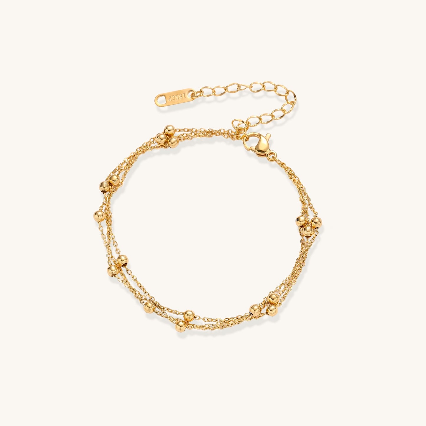Delicate 18K gold plated bracelet with spherical beads on layered chains and adjustable extender on white background