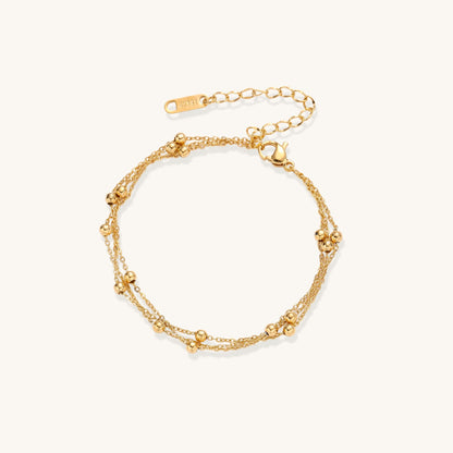 Delicate 18K gold plated bracelet with spherical beads on layered chains and adjustable extender on white background