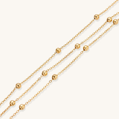 Delicate 18K gold plated bracelet with spherical beads on layered chains and adjustable extender on white background