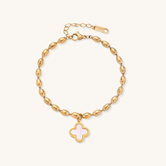 Dainty gold-plated beaded bracelet with oval links and four-leaf clover charm pendant on neutral background.