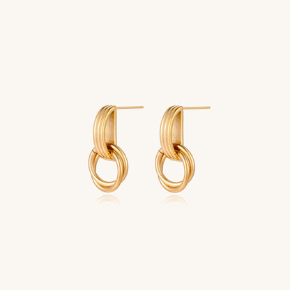 Geometric gold earrings with ribbed linear top section and circular drop elements on white background.