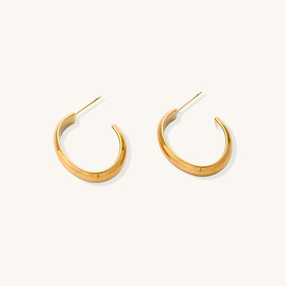 Four pairs of gold-plated stainless steel earrings including hoops and studs displayed on cream background