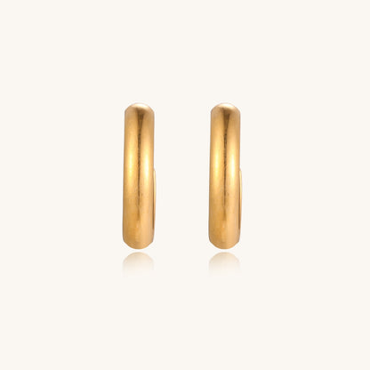 Four pairs of gold-plated stainless steel earrings including hoops and studs displayed on cream background