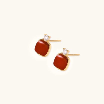 Gold-plated sterling silver stud earrings with square south red agate stones and clear crystals on cream background