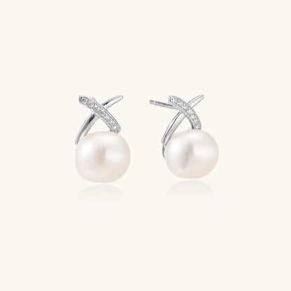 Sterling silver cross-shaped stud earrings with round freshwater pearls dangling below on white background.