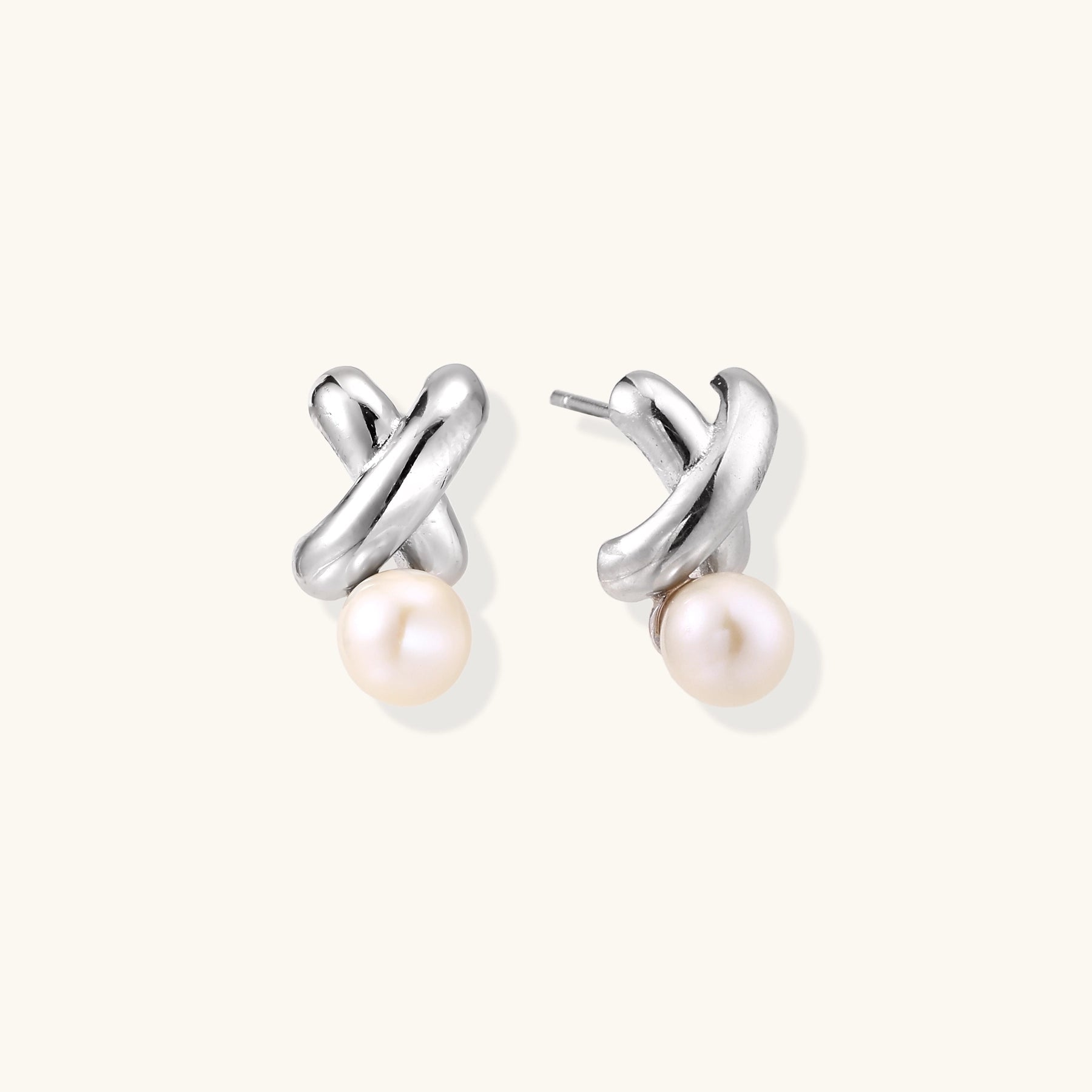 Sterling silver twisted stud earrings with round freshwater pearls on cream background, showing polished finish
