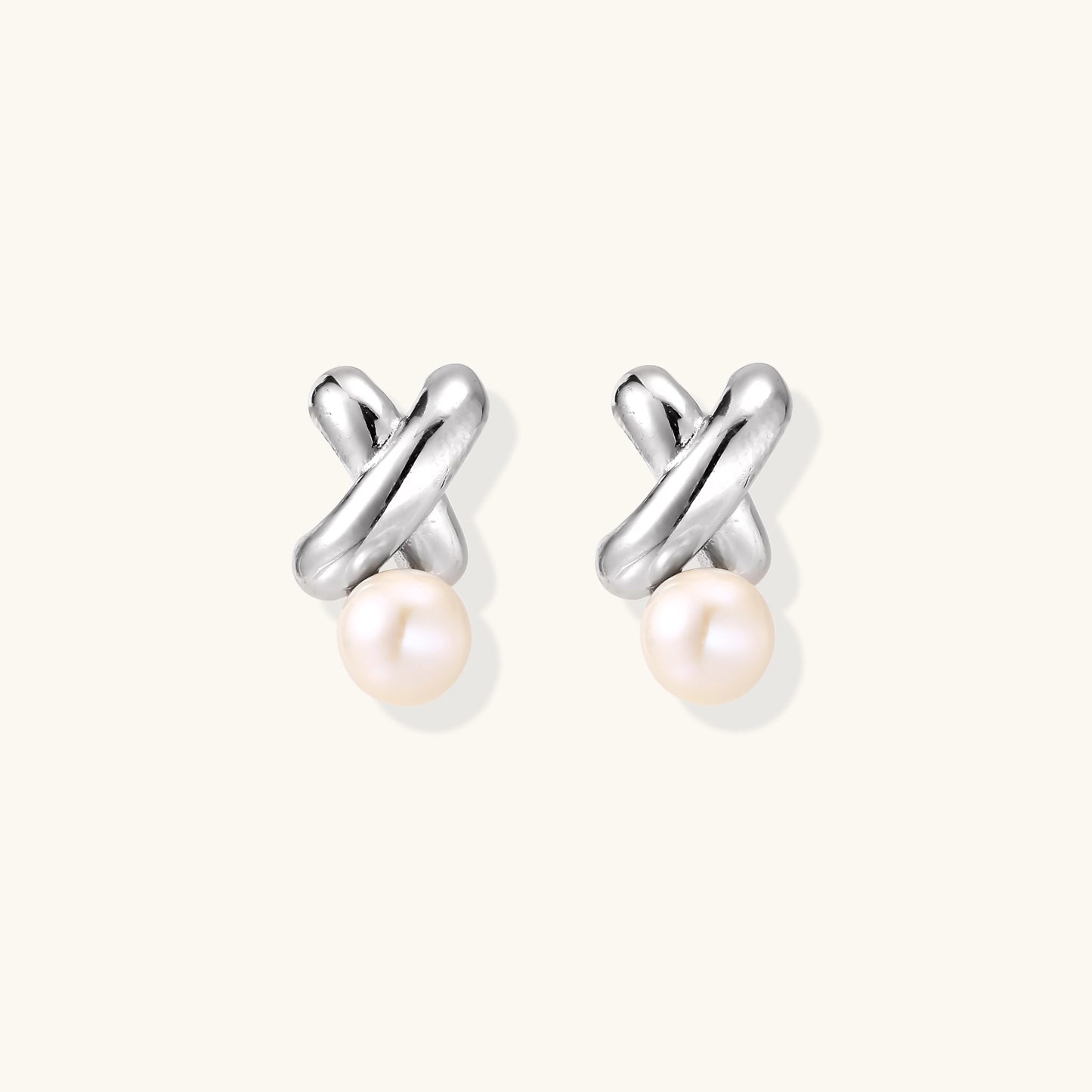 Sterling silver twisted stud earrings with round freshwater pearls on cream background, showing polished finish