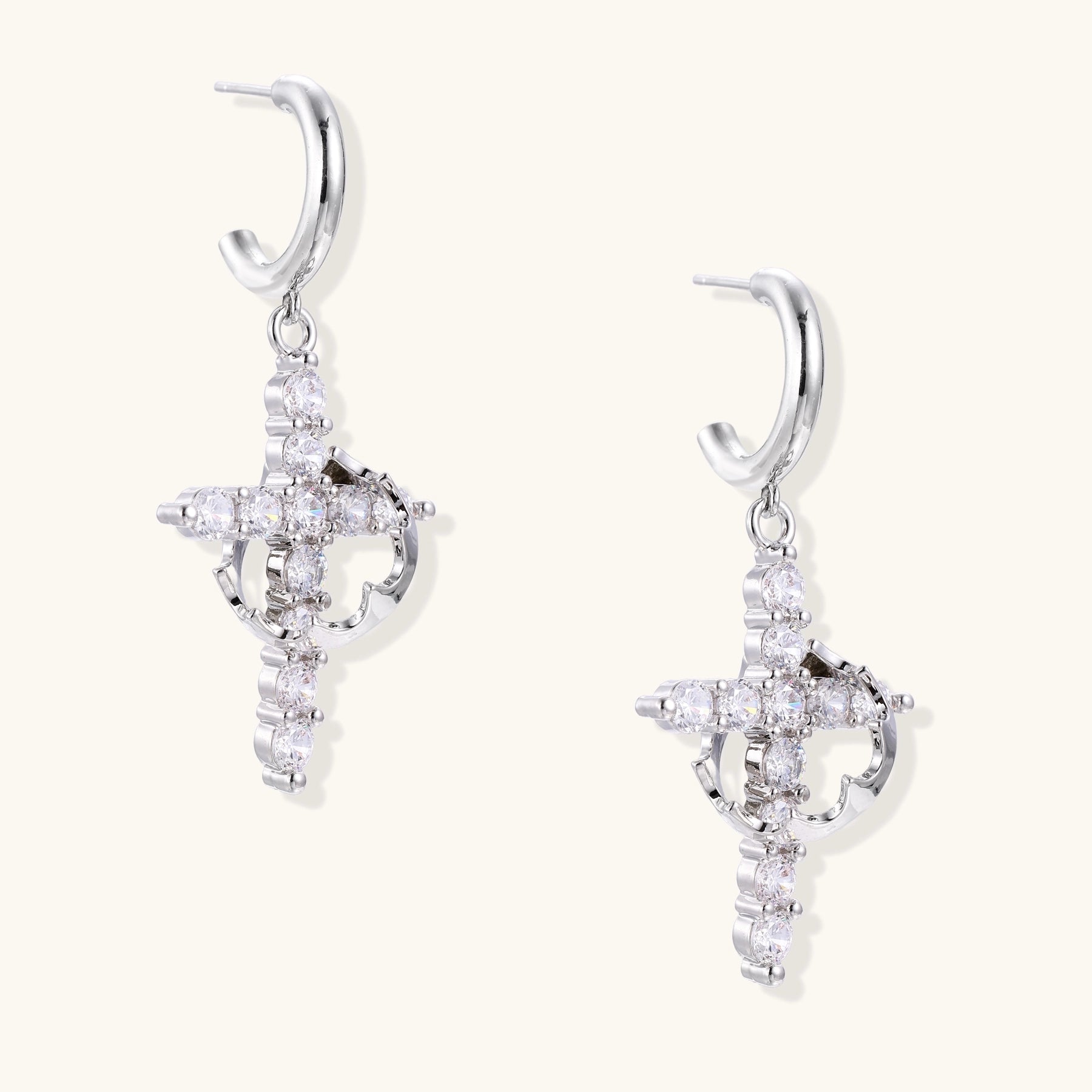Ornate cross dangle earrings with zirconia stones and gold-plated brass construction on white background.