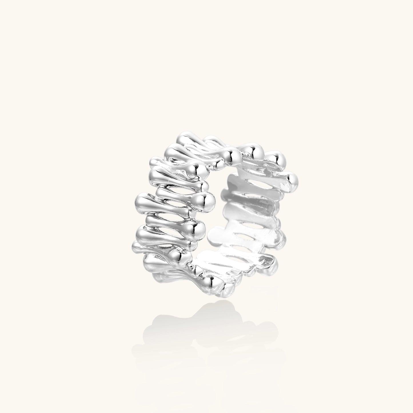 Close-up of an artistic gold-plated brass ring with multiple twisted bands creating a sculptural flowing design