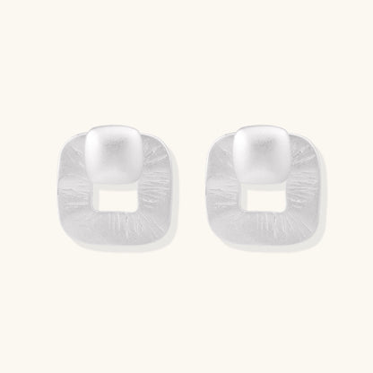 Geometric sterling silver square stud earrings with brushed texture and central square cutouts on white background.