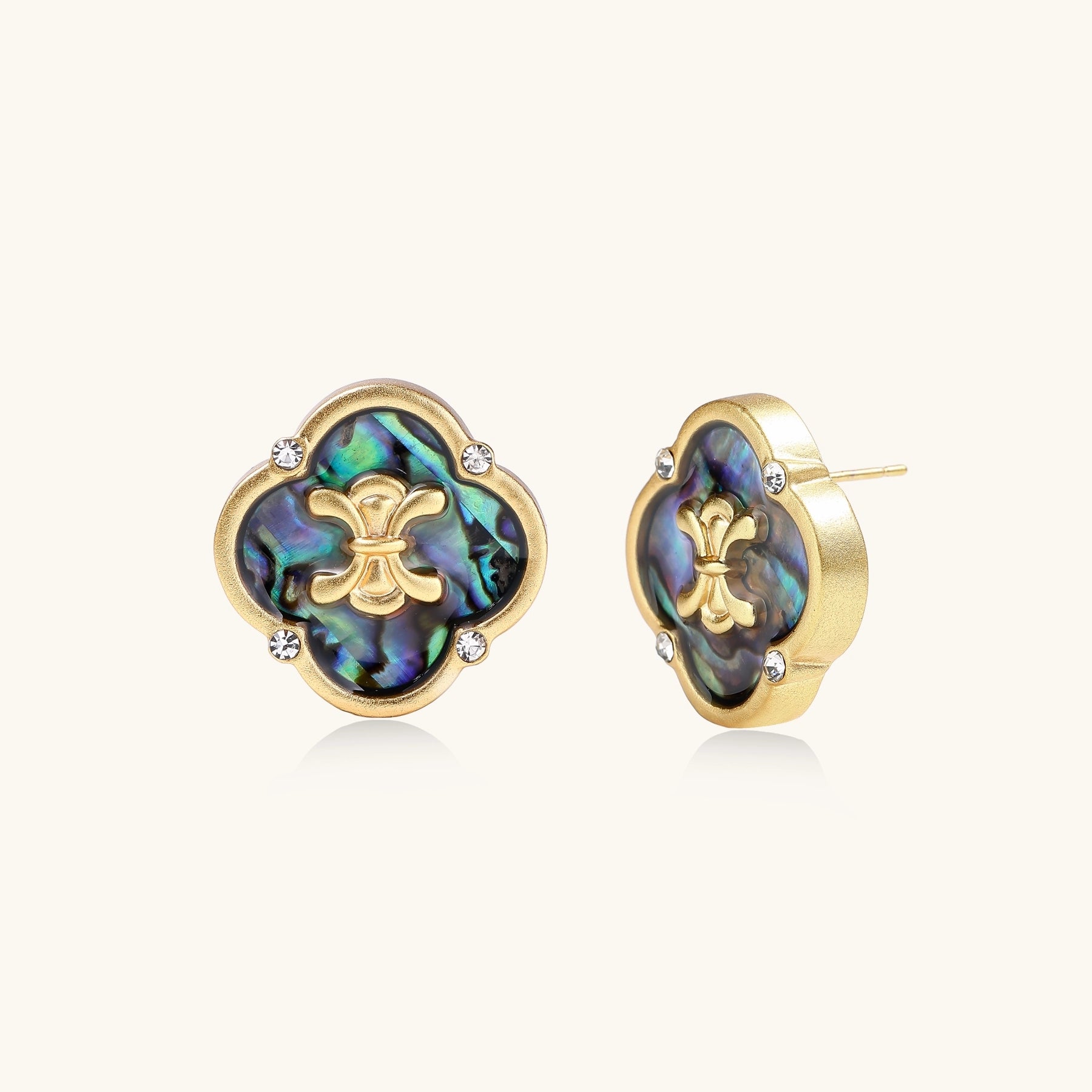 Gold-plated quatrefoil stud earrings featuring iridescent abalone shell centers with decorative motifs and crystal accents