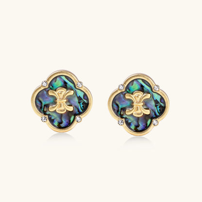 Gold-plated quatrefoil stud earrings featuring iridescent abalone shell centers with decorative motifs and crystal accents