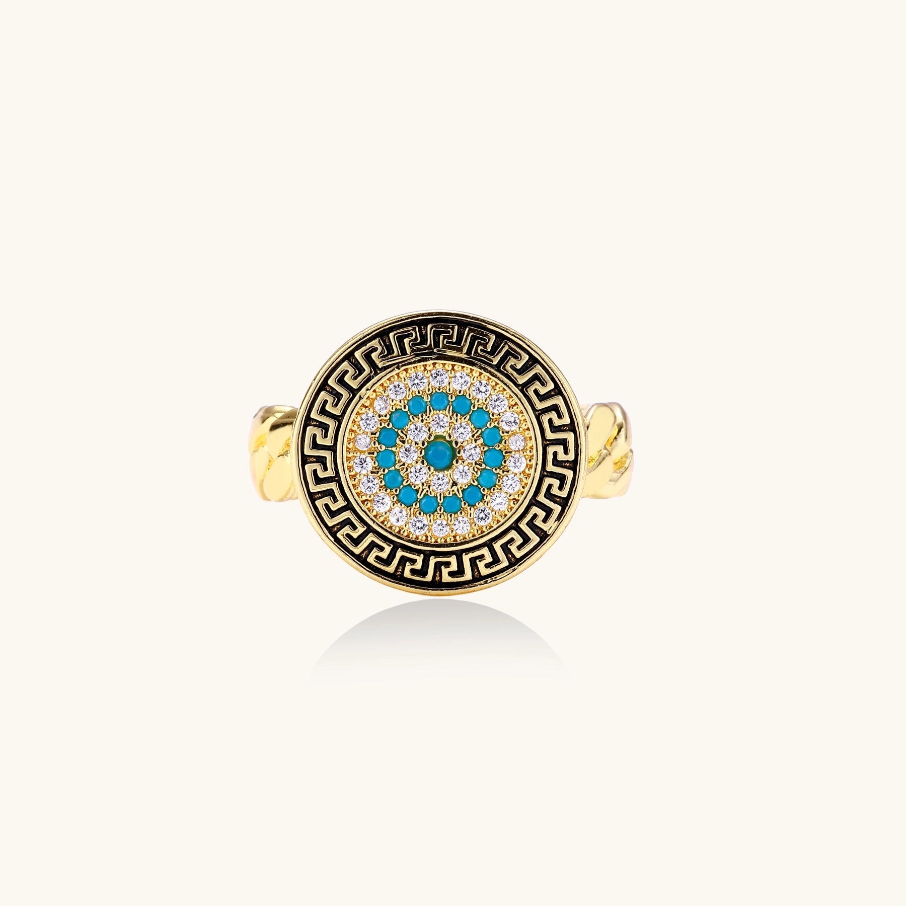 Gold-plated brass ring with Greek key border, evil eye center, and turquoise cubic zirconia stones in chunky chain band style.