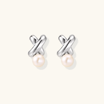 Rhodium-plated silver earrings with twisted X design and freshwater pearl drops on beige background