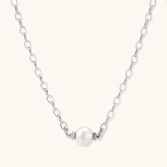 Dainty rhodium-plated silver chain necklace with centered 10mm freshwater pearl and crystal accents on cream background