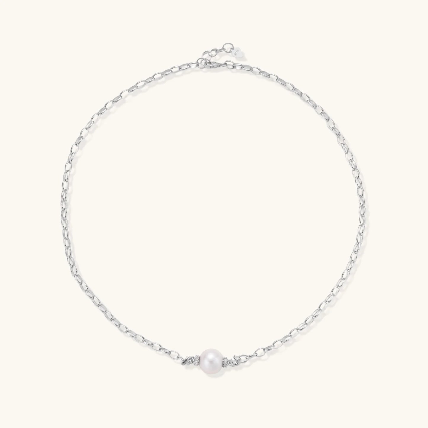 Dainty rhodium-plated silver chain necklace with centered 10mm freshwater pearl and crystal accents on cream background