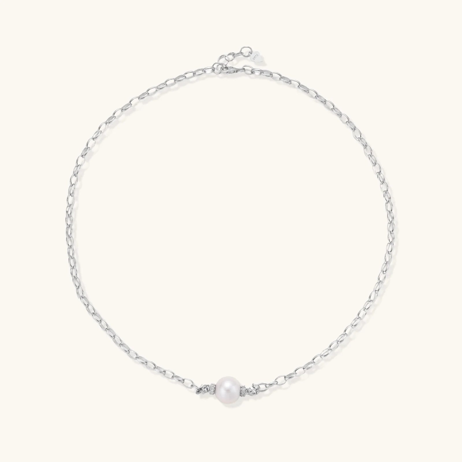 Dainty rhodium-plated silver chain necklace with centered 10mm freshwater pearl and crystal accents on cream background