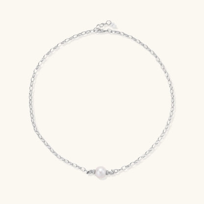 Dainty rhodium-plated silver chain necklace with centered 10mm freshwater pearl and crystal accents on cream background