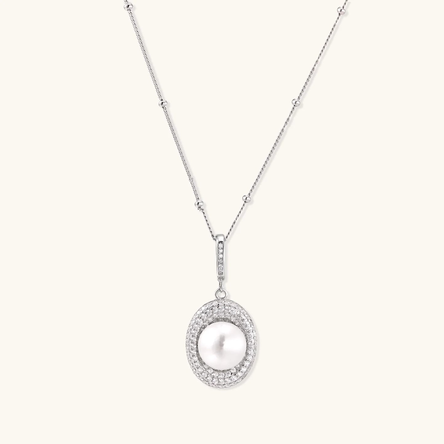 Oval sterling silver pendant with crystal halo surrounding a white freshwater pearl on delicate chain