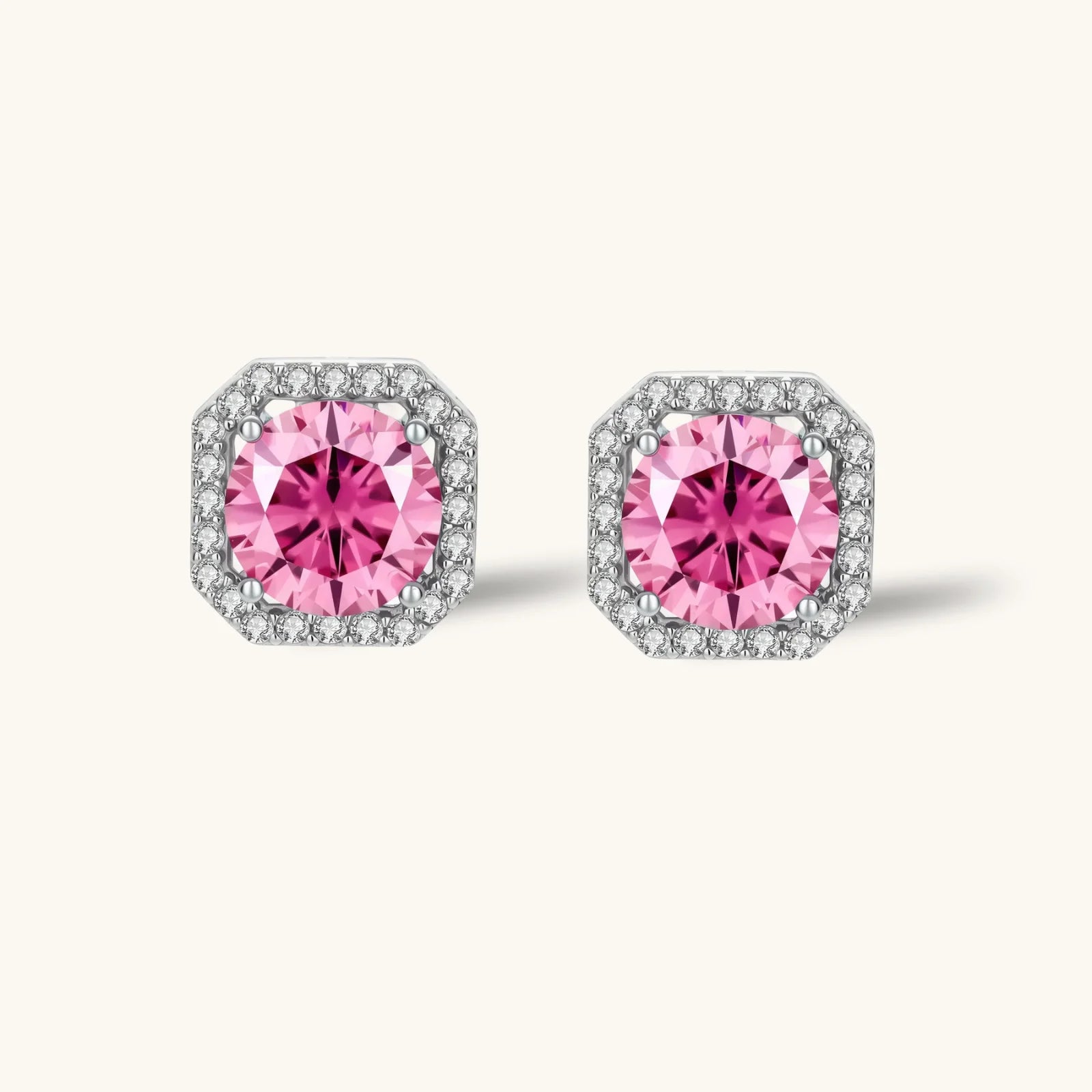 Pink moissanite studs in octagonal sterling silver halo settings with sparkling accent stones on cream background.