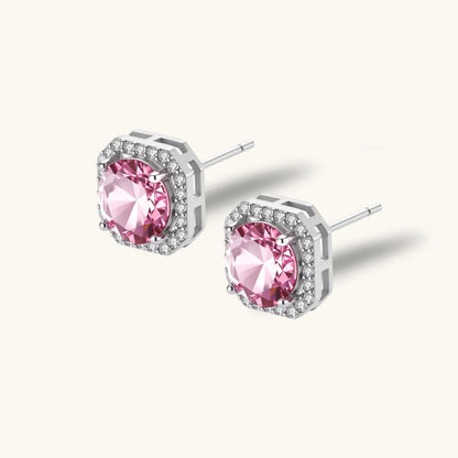 Pink moissanite studs in octagonal sterling silver halo settings with sparkling accent stones on cream background.