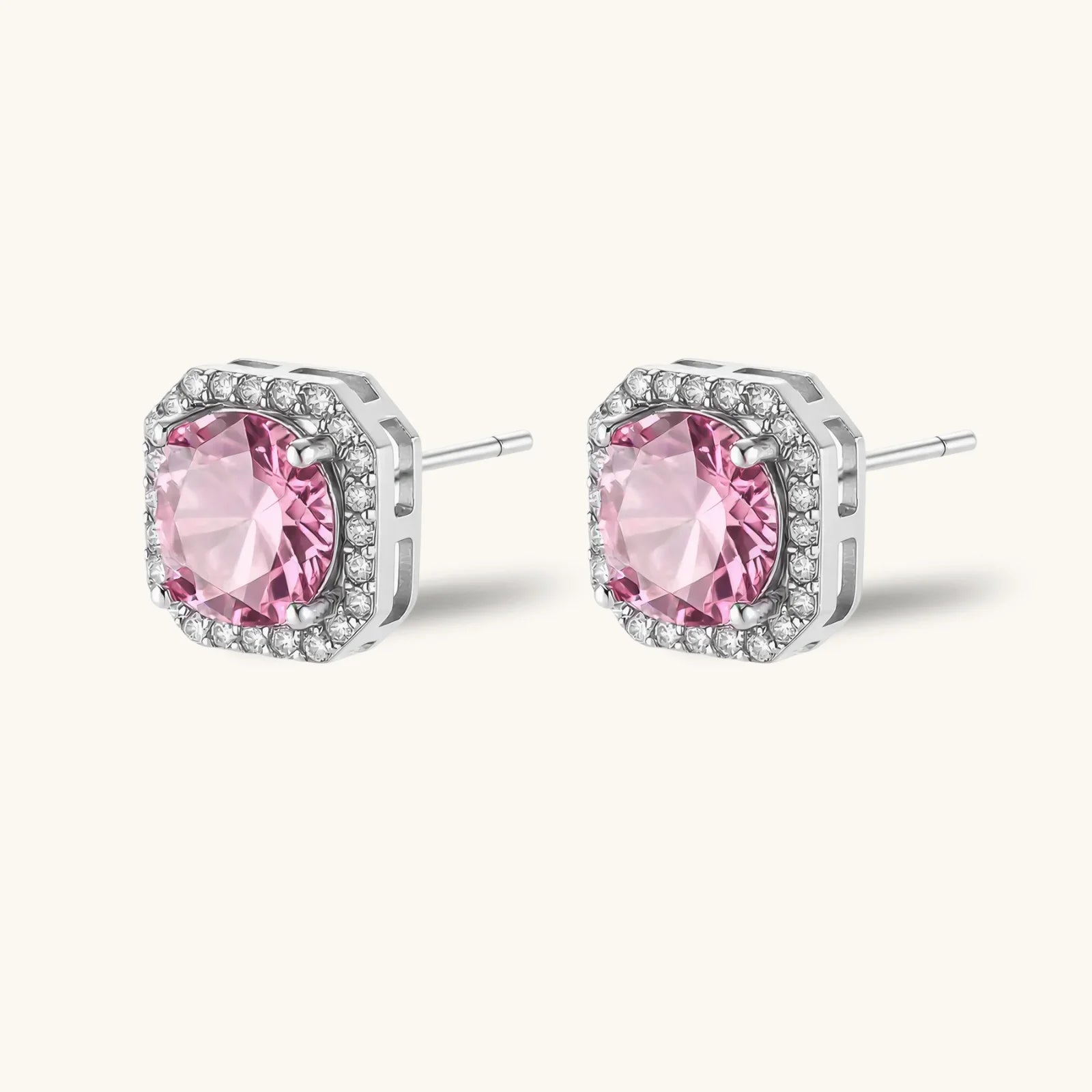 Pink moissanite studs in octagonal sterling silver halo settings with sparkling accent stones on cream background.
