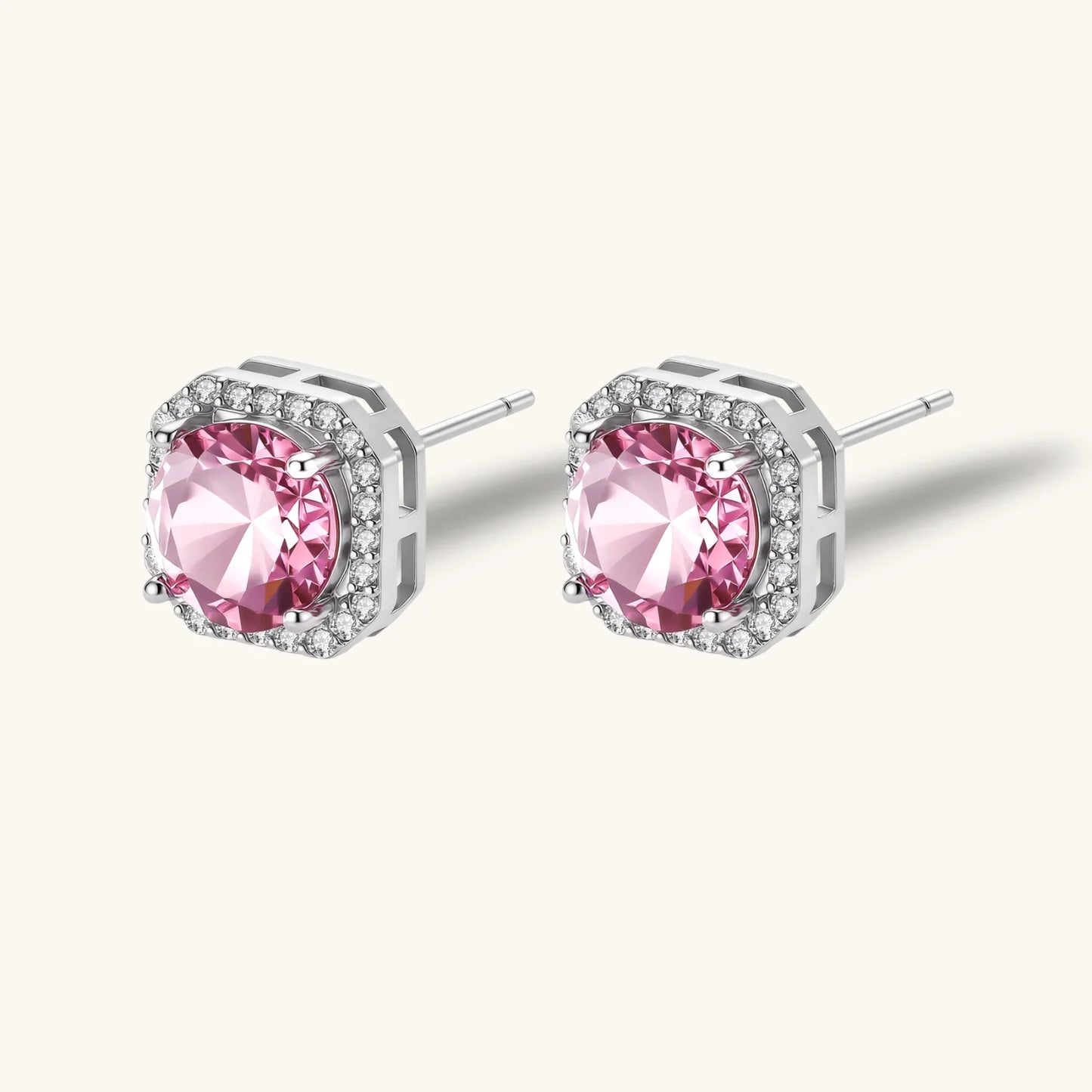 Pink moissanite studs in octagonal sterling silver halo settings with sparkling accent stones on cream background.