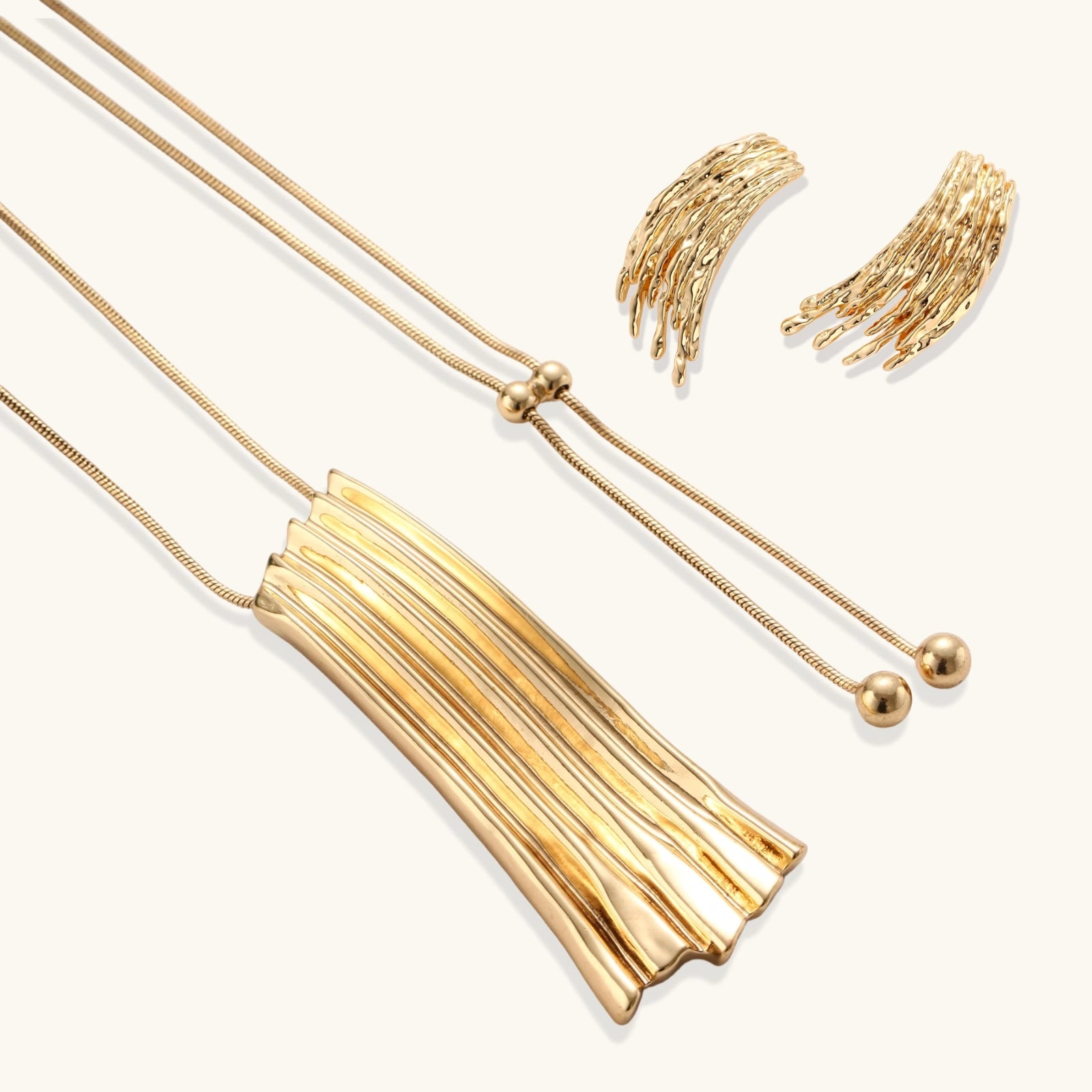 Gold-toned cascade jewelry set with flowing textured strands, featuring drop earrings and matching pendant necklace