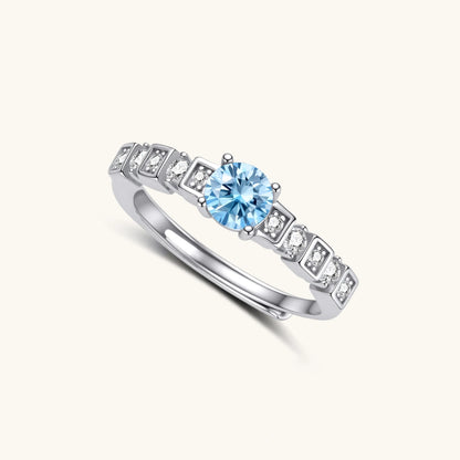 Geometric sterling silver ring with light blue moissanite center stone and square diamond accents on white background