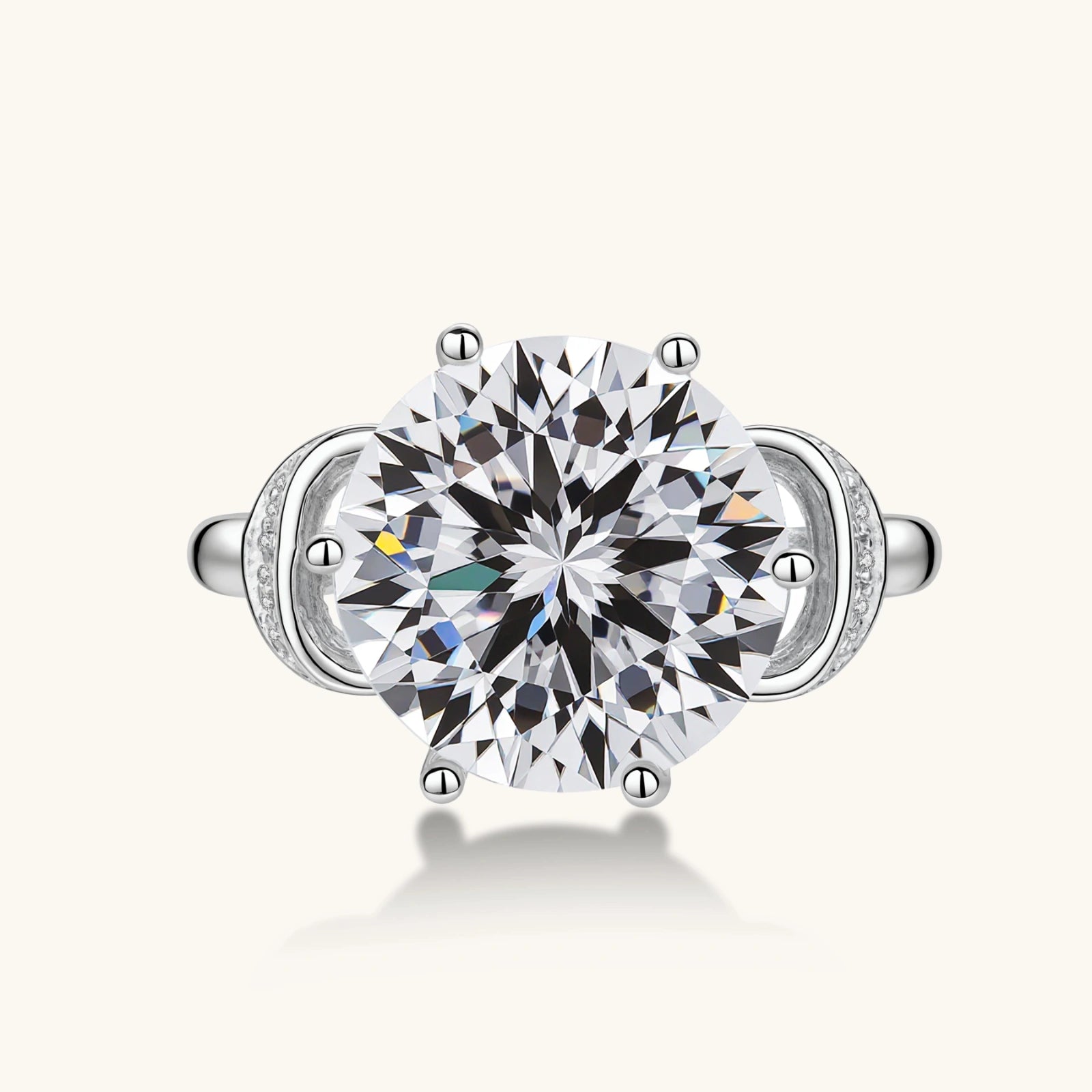 Sterling silver ring with 5ct round moissanite center stone and intricate bow design with pavé accents on white background.